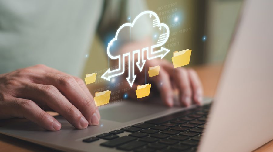 Hands typing on laptop with animated cloud syncing folders — automated, encrypted cloud backup and restore services by McNallan Technology Solutions Technology for Minnesota enterprises