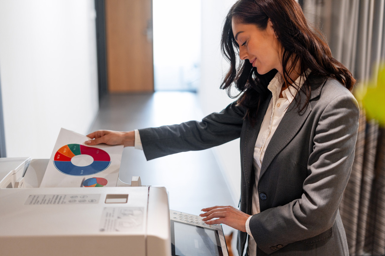 A smiling professional collecting printed reports from an office printer